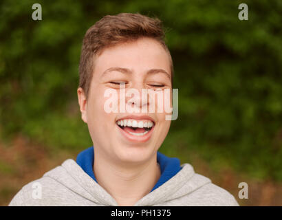 Happy teenager guy laughing with a natural background Stock Photo