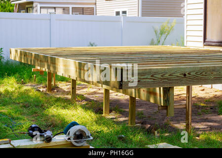 Deck construction work in garden with some torx circular saw, overlooking backyard landscape Stock Photo
