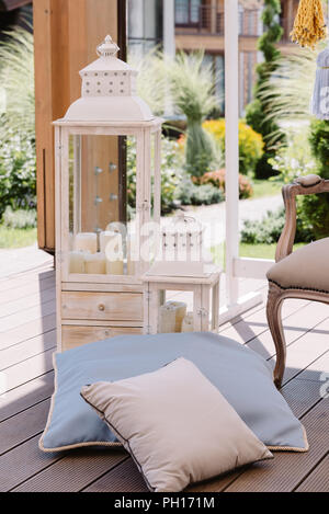 Candles in a wooden lamp and soft pillows. Stylish wedding details for a photoshoot Stock Photo