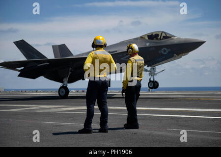 180820-N-FK070-1305 ATLANTIC OCEAN (Aug. 20, 2018) Aviation Boatswain's Mates (Handling) observe an F-35C Lightning II assigned to the Rough Raiders of Strike Fighter Squadron (VFA) 125 perform a touch-and-go landing on the flight deck of the Nimitz-class aircraft carrier USS Abraham Lincoln (CVN 72). (U.S. Navy photo by Mass Communication Specialist 1st Class Brian M. Wilbur/Released) Stock Photo