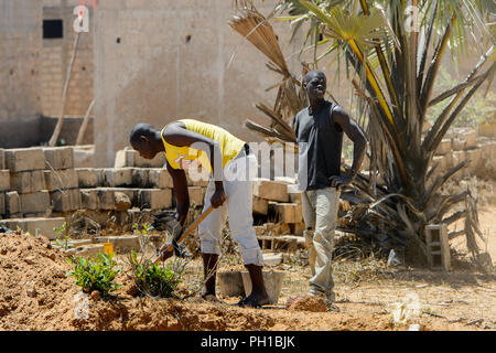 ROAD TO LAMPOUL, SENEGAL - APR 23, 2017: Unidentified Senegalese man holds a shovel and digs the ground. Still many people in Senegal live in poverty Stock Photo