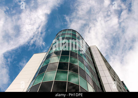 The combination of modern materials and colors of the modern business building. In the background is a beautiful sky with clouds. Stock Photo