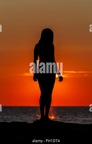 A woman is silhouetted at sunset on the jetty at Menemsha Beach in Chilmark, Massachusetts on Martha's Vineyard.