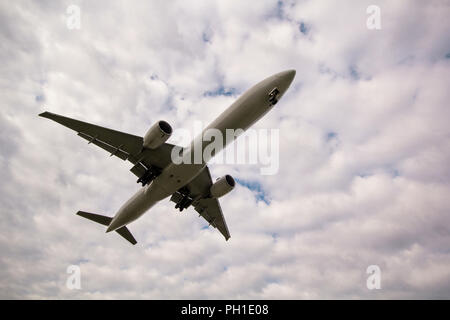 Overhead airplane on landing, seconds before landing. In the background is a beautiful sky with clouds. Stock Photo