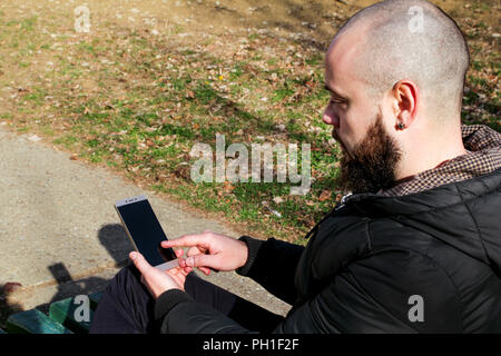 Silhouette of guy working with a smart phone and enjoying the fresh air in the park. Stock Photo
