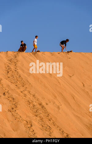 LAMPOUL DESERT, SENEGAL - APR 23, 2017: Unidentified tourist's little children stand on the top of sand dune in a Lampoul Desert, beautiful landscape  Stock Photo