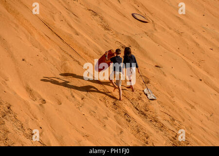 LAMPOUL DESERT, SENEGAL - APR 23, 2017: Unidentified tourist's little children climb on the top of sand dune in a Lampoul Desert, beautiful landscape  Stock Photo