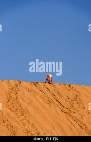 LAMPOUL DESERT, SENEGAL - APR 23, 2017: Unidentified tourist's little boy walks with the board to the top of sand dune in a Lampoul Desert, beautiful  Stock Photo