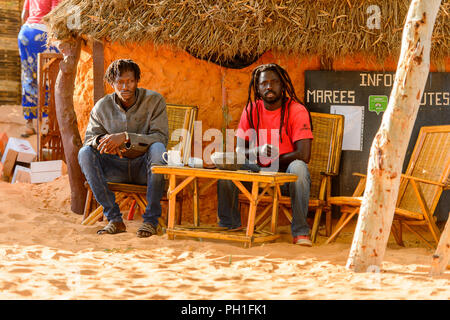 LAMPOUL DESERT, SENEGAL - APR 23, 2017: Unidentified Senegalese two men sit near the shack in a Lampoul Desert, beautiful landscape place Stock Photo