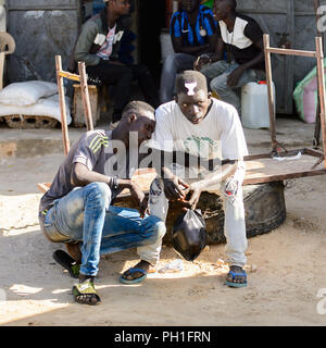 ROAD TO LAMPOUL, SENEGAL - APR 23, 2017: Unidentified Senegalese two men sit beside the road. Still many people in Senegal live in poverty Stock Photo