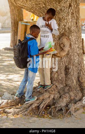 SAINT LOUIS, SENEGAL - APR 24, 2017: Unidentified Senegalese two little boys look at the book near the tree in Saint Louis, one of the biggest cities  Stock Photo