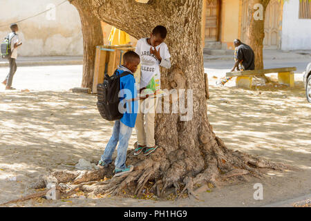 SAINT LOUIS, SENEGAL - APR 24, 2017: Unidentified Senegalese two little boys look at the book near the tree in Saint Louis, one of the biggest cities  Stock Photo