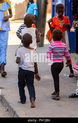 SAINT LOUIS, SENEGAL - APR 24, 2017: Unidentified Senegalese little children walk along the street in Saint Louis, one of the biggest cities in Senega Stock Photo