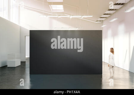 Woman stand near blank black wall mockup in modern white gallery. Girl walk near dark big stand mock up in museum with contemporary art exhibitions. L Stock Photo