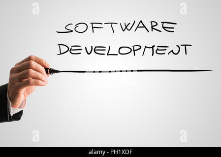 Hand of a man writing Software development on a virtual screen or interface with a marker pen with copyspace below. Stock Photo