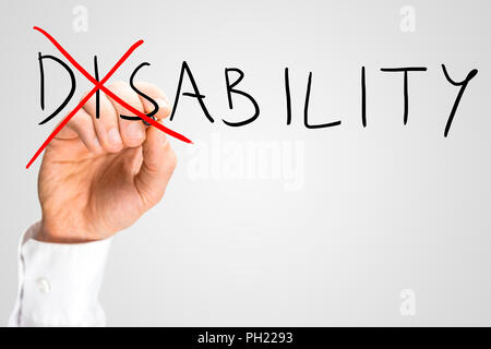 Overcoming a disability concept with a man writing the word Disability on a virtual interface and then crossing through the - Dis - with a red marker  Stock Photo