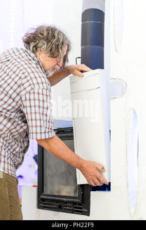 Close up of Old Man building a wall around a modern fireplace in an interior design concept. Stock Photo