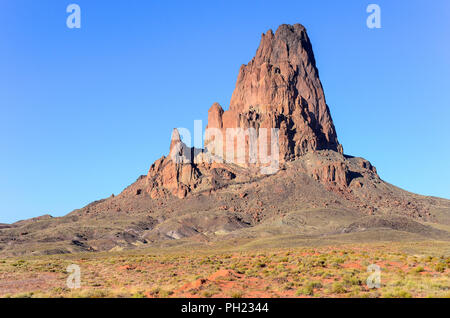 Agathla Peak, a rugged volcanic plug under a perfect blue sky in the landscape near Monument Valley, Arizona Stock Photo