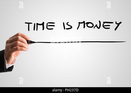 Man writing Time is money on a virtual screen or interface with a black marker over a light grey background with copyspace. Stock Photo