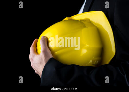 Close up view of a man in a suit holding a yellow hardhat under his arm conceptual of an architect, structural engineer, inspector or building contrac Stock Photo