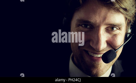 Portrait of young male customer service operator over black background, retro effect faded look. Stock Photo