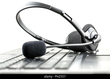 Headset lying on a laptop computer keyboard conceptual of telemarketing, call center, client services or online support. Stock Photo
