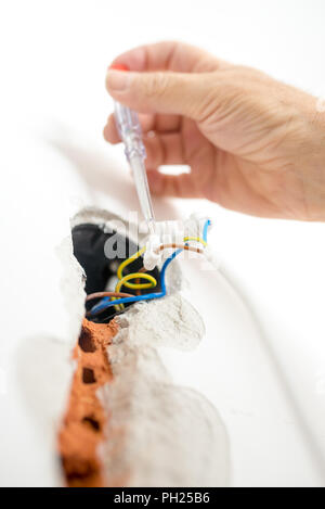 Closeup of hand of an electrician checking the presence of electrical current in newly installed house wiring. Stock Photo