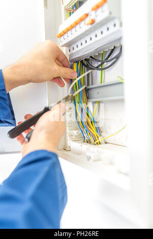 Electrician checking the wiring in a fuse box providing the electrical supply to a domestic residence either during installation as a new build or whe Stock Photo