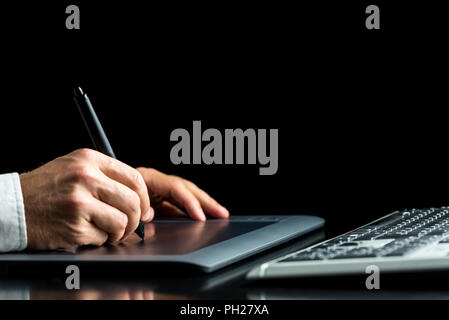Closeup of male graphic designer working on his digital tablet over black background. Stock Photo