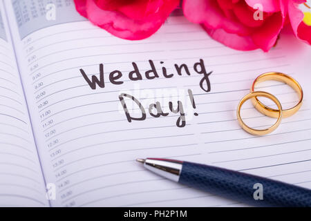 Two Golden Rings And Pen On Diary With Wedding Day Text Stock Photo