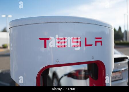 Close-up of Tesla Motors logo on Supercharger electric vehicle charging station, with automobile in background, in Pleasanton, California, July 23, 2018. () Stock Photo