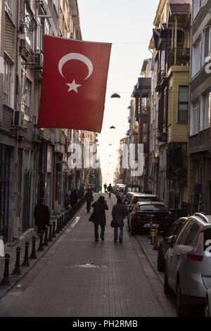 ISTANBUL, TURKEY - DECEMBER 27, 2015: Street of the district Kadikoy on the Asian side of Istanbul, with a Turkish flag hanging, at sunset  Picture of Stock Photo