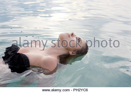 Young woman wearing black bikini floating in sea