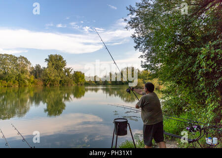 Fisherman on a lake in carp fishing action Stock Photo