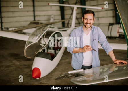 Handsome young pilot checking airplane  in the hangar Stock Photo