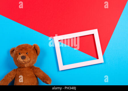 Teddy bear and white empty frame on colorful background Stock Photo