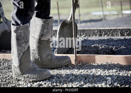 The boots of a mason working in cement with shallow depth of field Stock Photo