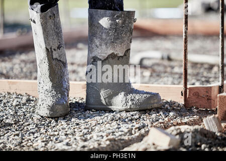 The boots of a mason working in cement with shallow depth of field Stock Photo