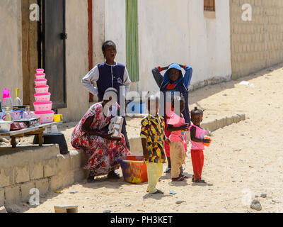 KAYAR, SENEGAL - APR 27, 2017: Unidentified Senegalese woman and little children stand beside the road in a beautiful village near Kayar, Senegal Stock Photo