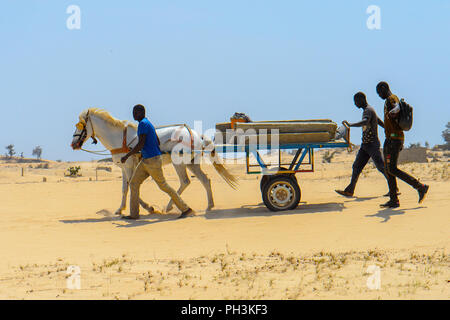 KAYAR, SENEGAL - APR 27, 2017: Unidentified Senegalese two men walk behind the cart along the road in a beautiful village near Kayar, Senegal Stock Photo