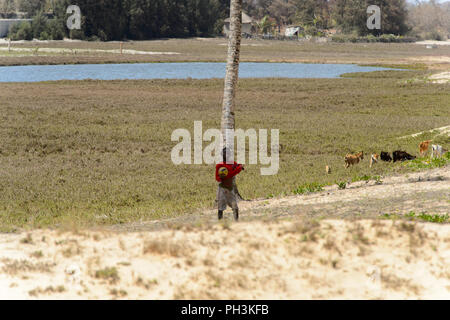 KAYAR, SENEGAL - APR 27, 2017: Unidentified Senegalese boy in red shirt stands with a ball in a beautiful village near Kayar, Senegal Stock Photo