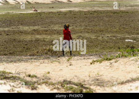 KAYAR, SENEGAL - APR 27, 2017: Unidentified Senegalese boy in red shirt stands with a ball in a beautiful village near Kayar, Senegal Stock Photo