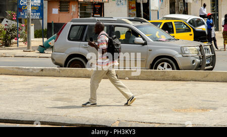 DAKAR, SENEGAL - APR 27, 2017: Unidentified Senegalese man with backpack walks along the street in Dakar, the capital of Senegal Stock Photo