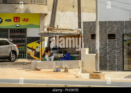 DAKAR, SENEGAL - APR 27, 2017: Unidentified Senegalese two men sit beside the road under the roof in Dakar, the capital of Senegal Stock Photo
