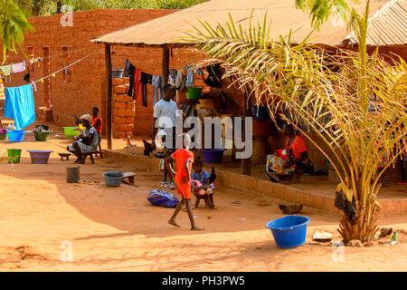 ROAD TO BISSAU, GUINEA B. - MAY 1, 2017: Unidentified local people near their house in a village in Guinea Bissau. Still many people in the country li Stock Photo