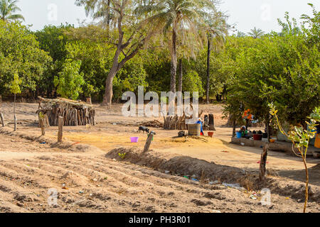 ROAD TO BISSAU, GUINEA B. - MAY 1, 2017: Unidentified local woman washes clothes in a village in Guinea Bissau. Still many people in the country live  Stock Photo