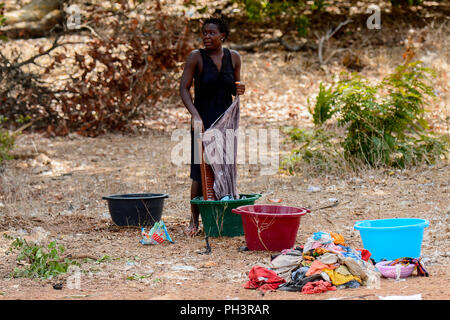 ROAD TO BISSAU, GUINEA B. - MAY 1, 2017: Unidentified local woman washes the clothes in a village in Guinea Bissau. Still many people in the country l Stock Photo