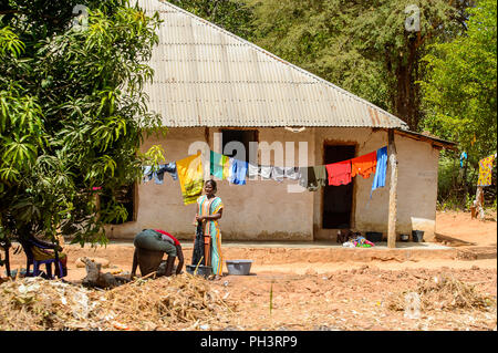 ROAD TO BISSAU, GUINEA B. - MAY 1, 2017: Unidentified local woman washes clothes in a village in Guinea Bissau. Still many people in the country live  Stock Photo