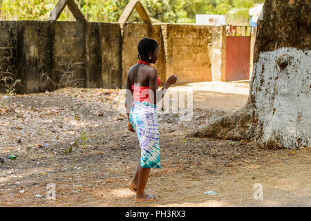 ROAD TO BISSAU, GUINEA B. - MAY 1, 2017: Unidentified local beautiful woman with short haircut stands in a village in Guinea Bissau. Still many people Stock Photo