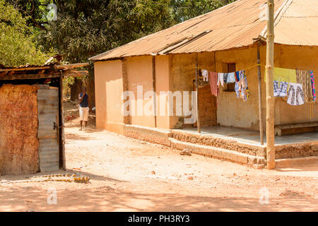 ROAD TO BISSAU, GUINEA B. - MAY 1, 2017: Unidentified local man walks near the house in a village in Guinea Bissau. Still many people in the country l Stock Photo